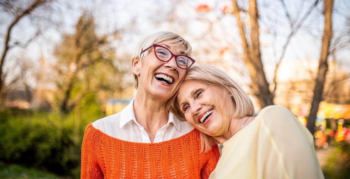 Two older women smiling and leaning on each other
